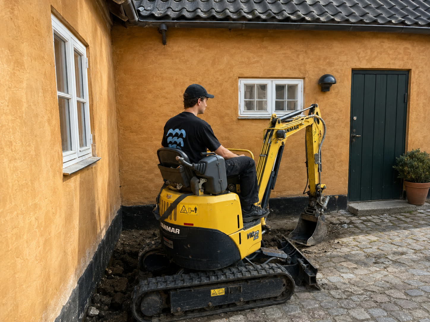 Minigraver fra Øresund Ejendomsservice udfører gravearbejde i en smal gård