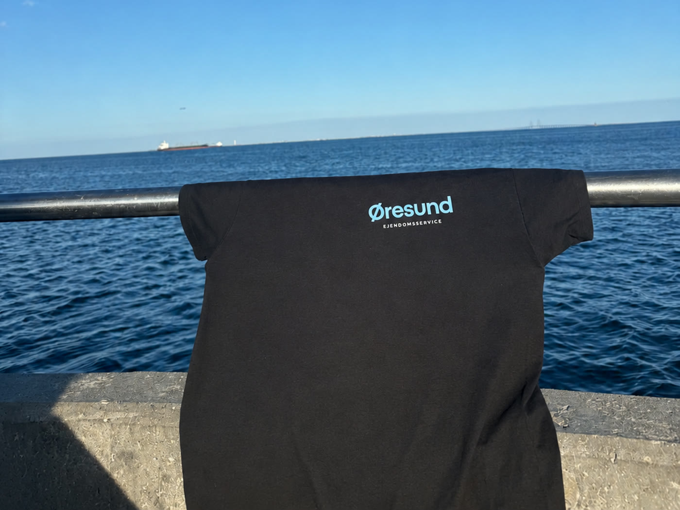 Øresund Ejendomsservices firmatrøje med logo hængt op ved Øresund